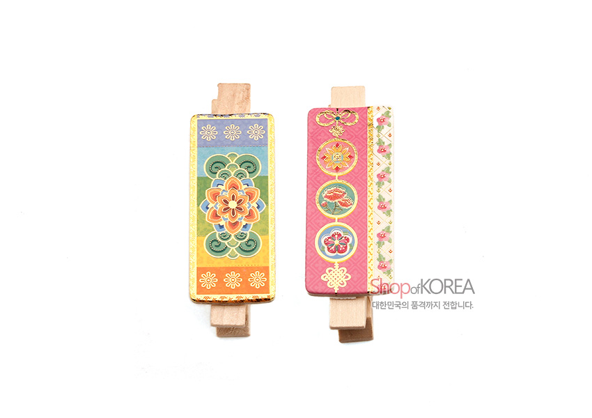 [텍스트: ShopofKOREA 대한민국의 품격까지 전합니다.] 나무 클립 위 금속판에 다채로운 파스텔 톤 전통 꽃문양과 원형 문양, 금빛 테두리로 장식된 자석 메모 집게 디자인