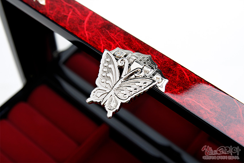 [텍스트: 샵오브코리아 대한민국의 전통거리를 전합니다.] 붉은 옻칠 한지 표면과 은색 나비 모양 금속 잠금장치, 내부 붉은 완충 칸막이 조화 모습