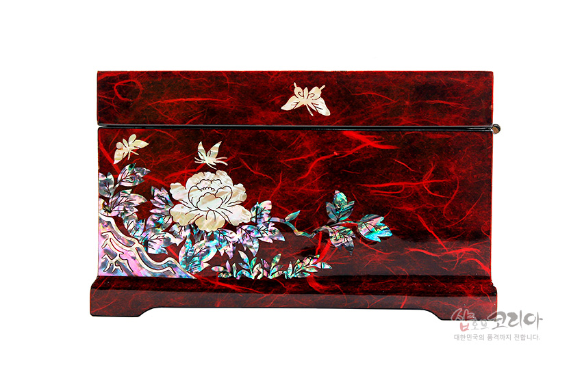 [텍스트: 샵오브코리아 대한민국의 품격까지 전합니다.] 붉은 옻칠 한지 표면 위 자개 상감 기법으로 목단과 나비 문양을 섬세하게 장식한 직사각형 보석함 이미지 설명