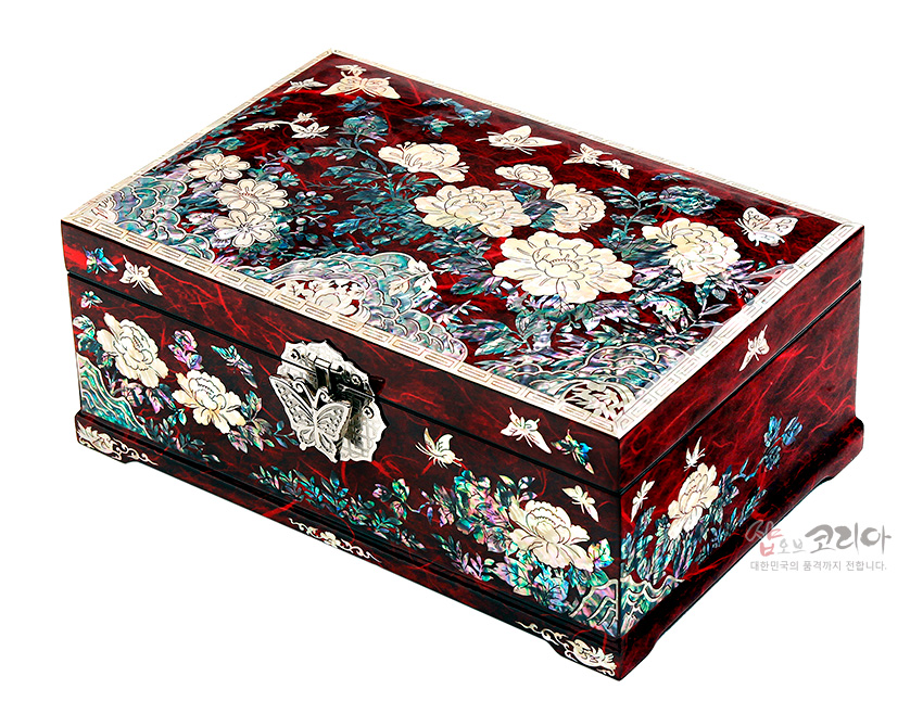 [텍스트: 샵오브코리아 대한민국의 품격까지 전합니다.] 붉은 옻칠 한지 위 자개 상감으로 목단과 나비 문양을 섬세하게 장식한 직사각형 금속 잠금 보석함 이미지 설명