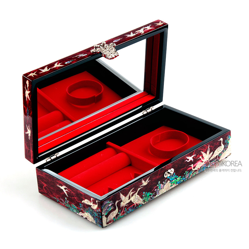 [텍스트: ShopofKOREA 대한민국의 품격까지 전합니다.] 적색 한지 바탕 위 자개 상감으로 송학·소나무·구름 문양을 둘러 장식하고 내부는 붉은 완충 재질과 거울로 구성된 직사각 보석함 이미지