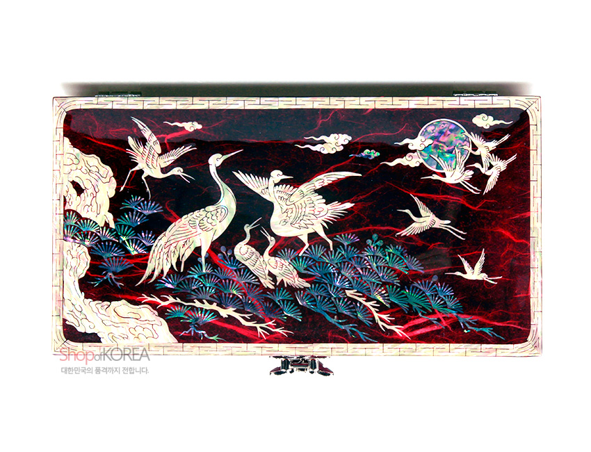 [텍스트: shopKOREA 대한민국의 품격까지 전합니다.] 적색 한지 위에 자개 상감 기법으로 송학과 소나무, 구름과 달 문양을 섬세하게 표현한 직사각형 보석함 모습