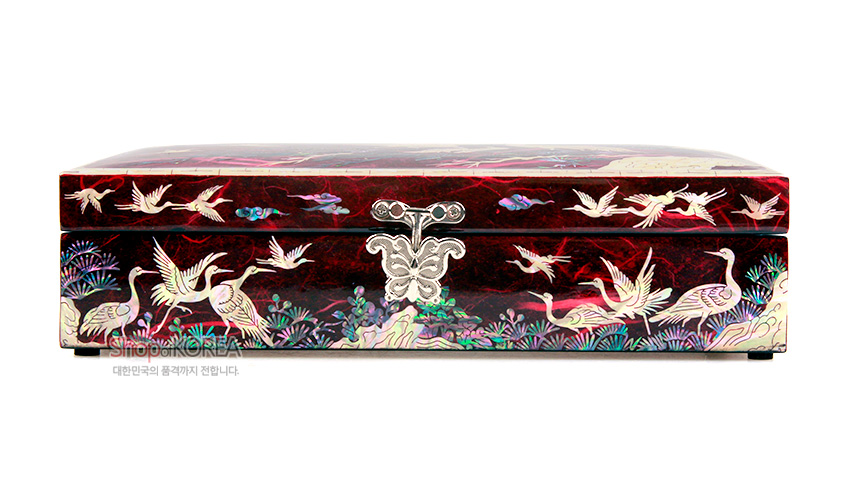 [텍스트: ShopofKOREA 대한민국의 품격까지 전합니다] 적색 한지 위 자개 상감 기법으로 송학과 구름, 수초 문양을 섬세하게 배치한 직사각 보석함 정면 장식 표현