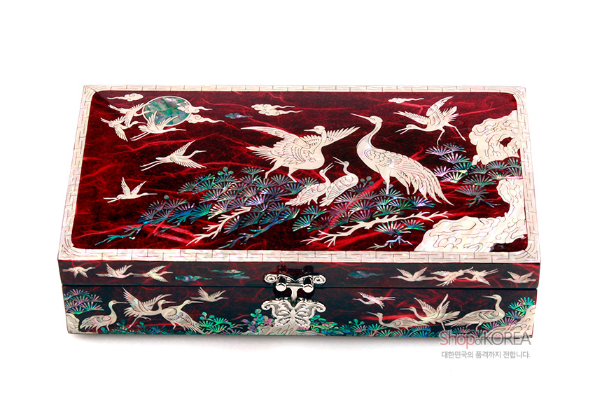 [텍스트: ShopKOREA 대한민국의 품격까지 전합니다.] 적색 한지 위 자개 상감 기법으로 송학과 소나무, 구름, 산수 문양을 정교하게 표현한 직사각 보석함 디자인