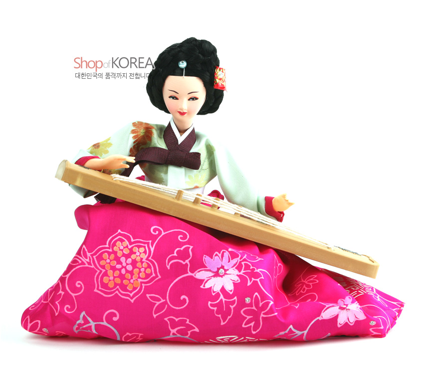 [텍스트: Shop of KOREA 대한민국의 품격까지 전합니다] 분홍 꽃문양 비단치마와 연두색 저고리의 한복, 나무 재질 가야금을 연주하는 전통 인형 장식 모습