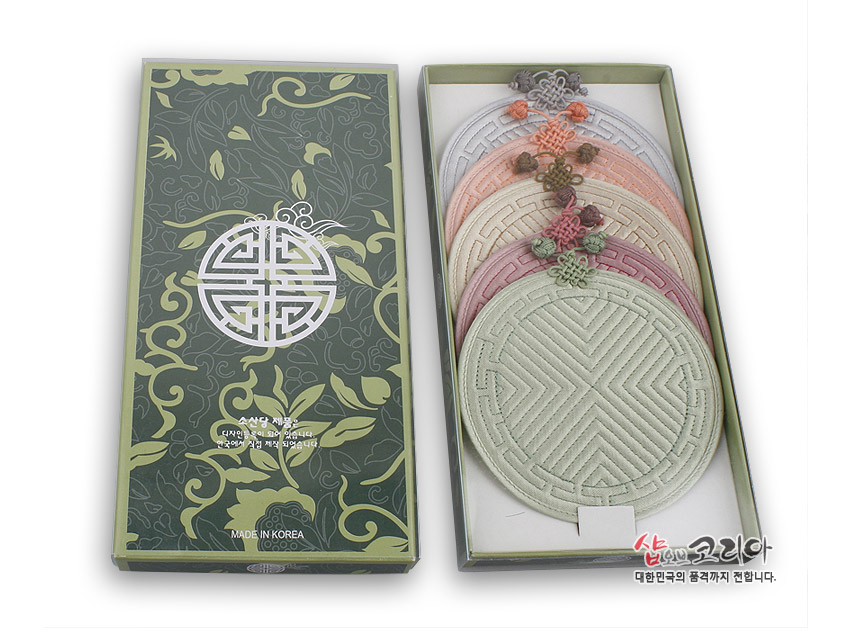 [텍스트: MADE IN KOREA, 샵오브코리아 대한민국의 품격까지 전합니다.] 파스텔 톤 원형 누비 컵받침 5종과 전통 문양 포장 상자, 기하학 누비선과 배씨머리 매듭 장식 특징 이미지