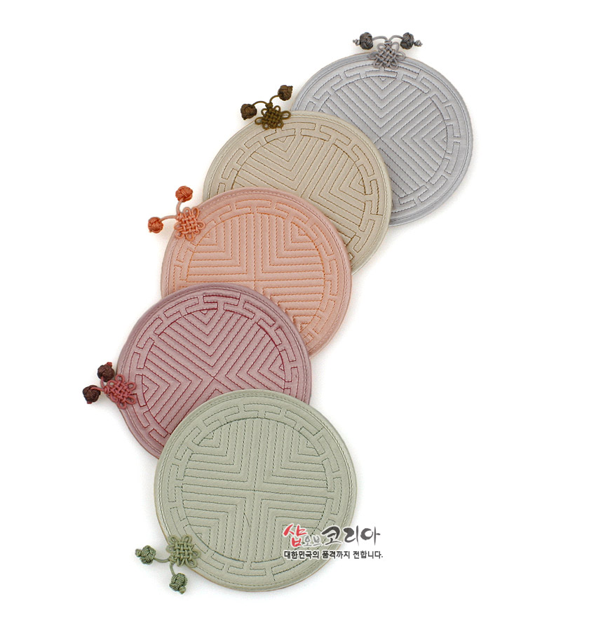 [텍스트: 샵오브코리아 대한민국의 품격까지 전합니다.] 파스텔 톤 천 소재에 전통 누비 기법으로 기하학 문양을 넣고 배씨머리 매듭 장식을 더한 원형 컵받침 5종 구성