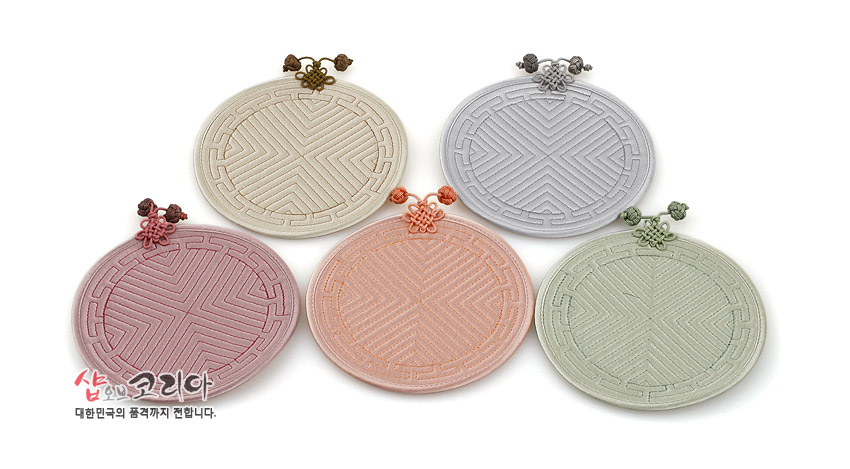 [텍스트: 샵오브코리아 대한민국의 품격까지 전합니다.] 파스텔 톤 천 소재에 전통 누비 기법으로 기하학 문양을 넣고 배씨머리 매듭 장식을 더한 원형 컵받침 5종 구성