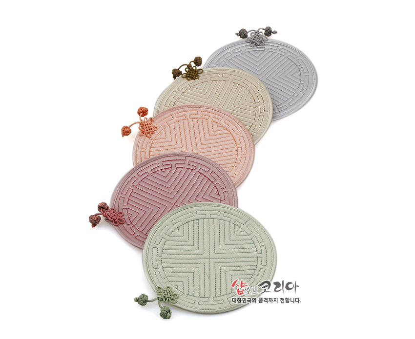 [텍스트: 샵오브코리아 대한민국의 품격까지 전합니다.] 파스텔 톤 천 소재에 전통 누비 기법으로 기하학 문양을 넣고 배씨머리 매듭 장식을 더한 원형 컵받침 5종 구성