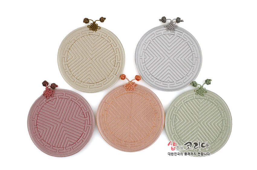 [텍스트: 샵오브코리아 대한민국의 품격까지 전합니다.] 파스텔 톤 원단에 전통 누비 기법으로 기하학 문양을 넣고 상단에 배씨머리 매듭을 단 원형 컵받침 5종 구성