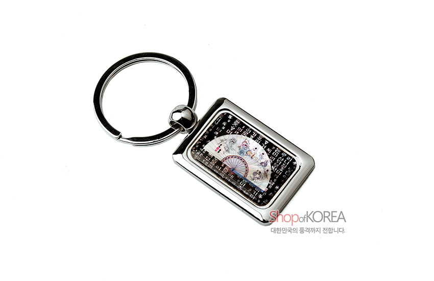 [텍스트: Shop of KOREA 대한민국의 품격까지 전합니다.] 금속 사각 테두리 안에 흑색 바탕 자개 상감, 중앙 반원 부채와 훈민정음 글자 문양이 은은한 오방색 광택으로 장식된 열쇠고리 디자인