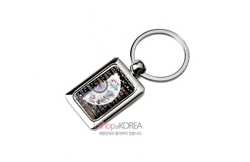 [텍스트: Shop of KOREA, 대한민국의 품격까지 전합니다.] 금속 사각 프레임 안 자개 상감으로 반원 부채와 훈민정음 문자 문양을 넣은 열쇠고리 디자인