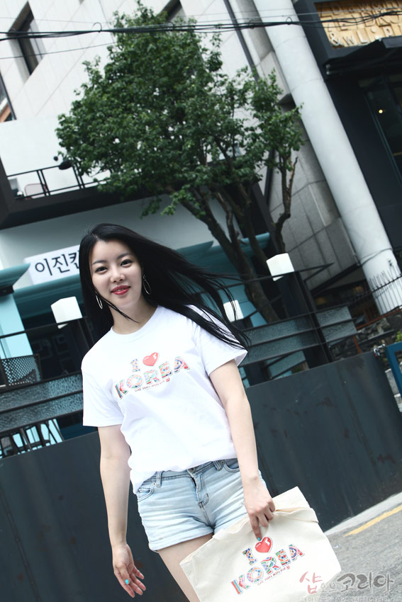 [텍스트: I ♥ KOREA] 흰색 면 티셔츠에 다채로운 전통 문양이 채워진 입체발포 영문 로고가 전면에 배치된 반팔 티셔츠 연출 이미지