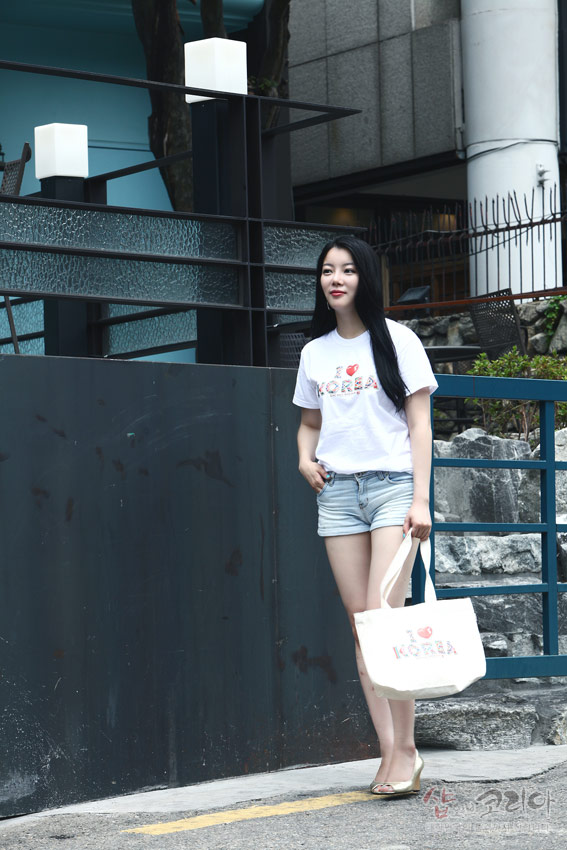 [텍스트: I ♥ KOREA] 흰색 면 티셔츠와 에코백에 3D 입체발포 기법으로 표현된 영문 문구와 전통문양 패턴이 더해진 캐주얼 코디 연출 모습