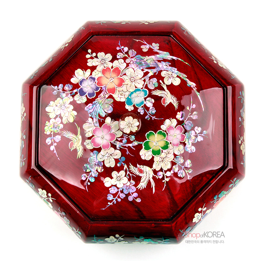 [텍스트: shopofKOREA 대한민국의 품격까지 전합니다.] 붉은 옻칠 바탕 위에 오각 자개 상감으로 매화와 꽃, 화조문을 섬세하게 배치한 팔각 나전칠기 다용도함 상판 장식