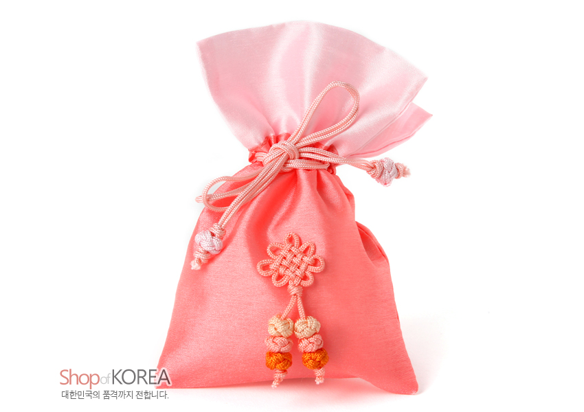 [텍스트: Shop of KOREA / 대한민국의 품격까지 전합니다.] 담주색 계열 비단 소재 복주머니, 상단 연분홍 비단 배색과 끈 매듭, 전면 연분홍 꽃매듭과 하단 다색 매듭술 장식 이미지설명