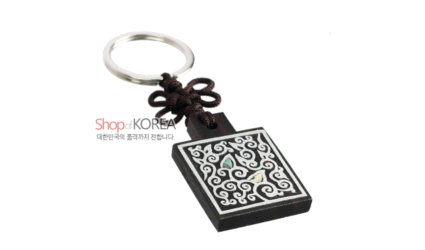 [텍스트: Shop of KOREA 대한민국의 품격까지 전합니다.] 흑단 사각판 위 흰색 선으로 구름문양 상감, 자개 포인트 장식과 갈색 전통 매듭, 금속 링 결합 열쇠고리 형식