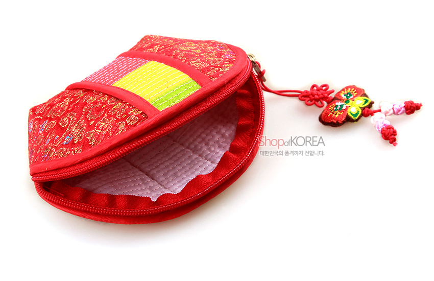 [텍스트: Shop of KOREA 대한민국의 품격까지 전합니다.] 붉은 비단 바탕에 금색 전통문양과 누비 처리, 중앙 색동띠와 자수 노리개 매듭 장식의 반달형 동전지갑 모습