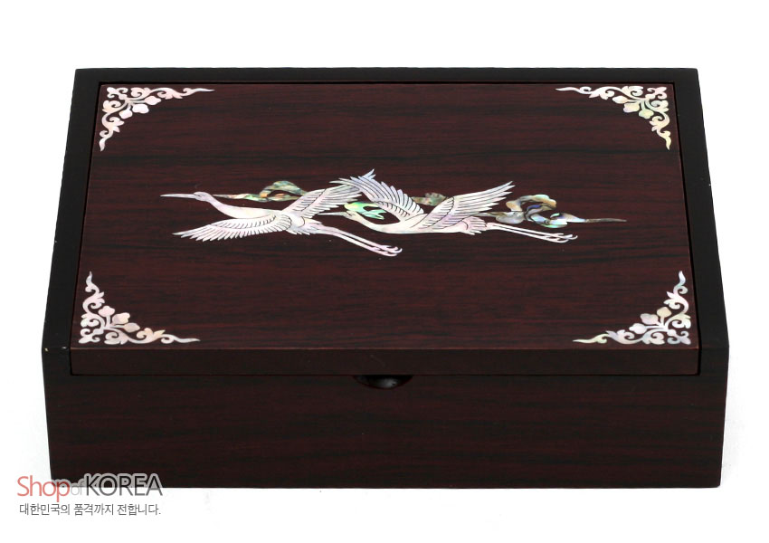 [텍스트: Shop KOREA 대한민국의 품격까지 전합니다.] 짙은 갈색 옻칠 목재 위 자개 상감 기법으로 구름과 학 문양을 새기고, 네 모서리에 백색 곡선 장식을 더한 직사각 명함함 이미지