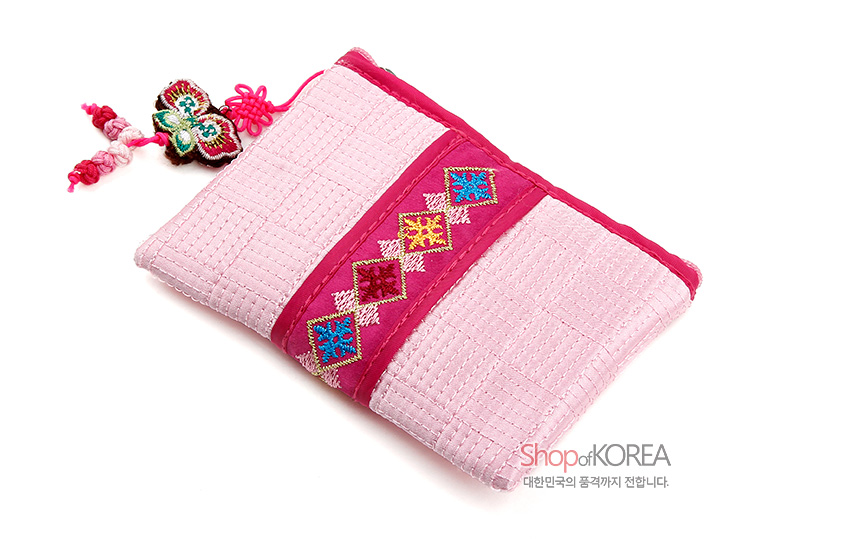 [텍스트: Shop of KOREA 대한민국의 품격까지 전합니다.] 연분홍 누빔 비단에 진분홍 띠와 사각 전통 자수문, 나비 모양 매듭 장식이 조화를 이룬 동전지갑 모습