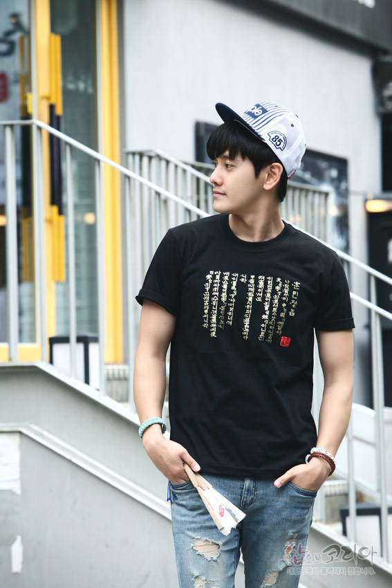 [텍스트: 훈민정음 언해 일부 한글 세로글씨와 붉은색 직인] 검은색 면 티셔츠에 금색 입체발포 기법으로 세로 배열된 훈민정음 서체 장식