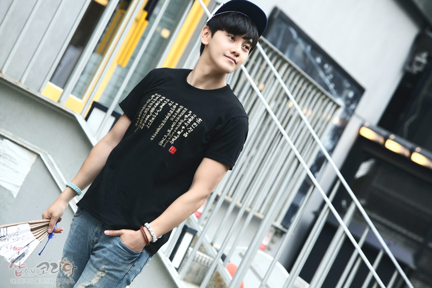 [텍스트: 훈민정음] 검은색 면 소재 위에 금색 입체 발포 기법으로 훈민정음 서체를 세로 배열한 반소매 티셔츠 디자인