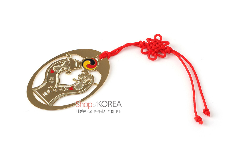 [텍스트: 天下一장군] 금장 금속책갈피에 양각 장승 문양과 태극 원형 장식, 붉은 전통 매듭끈 술이 조화된 디자인