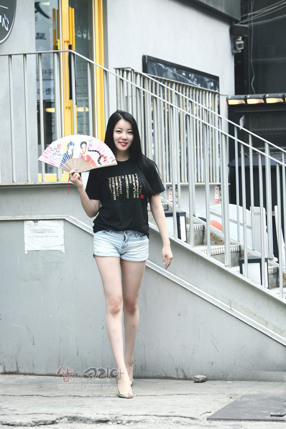 [텍스트: 샵오브코리아] 검은색 면 티셔츠 위에 금색 입체 발포 기법으로 표현된 훈민정음 한글 서체와 빨간색 포인트 글씨가 들어간 캐주얼 반소매 디자인