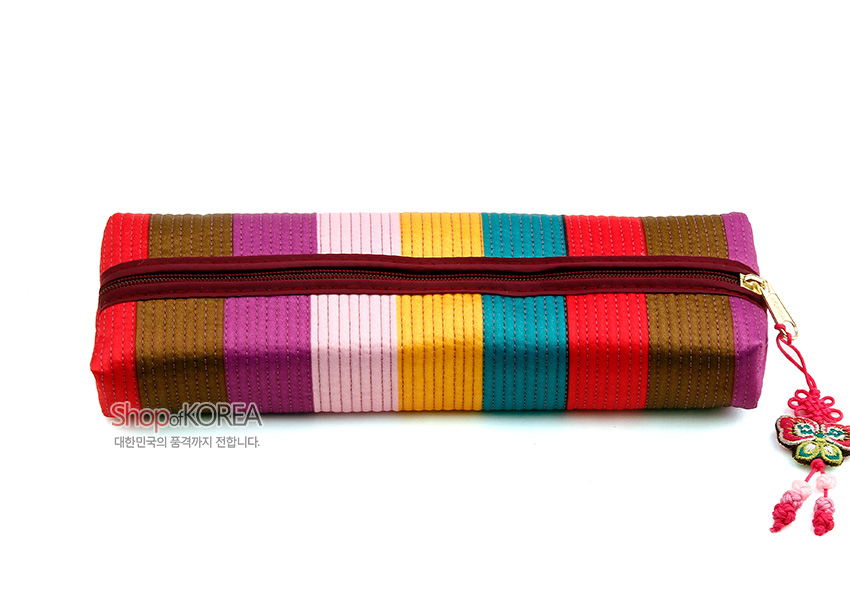 [텍스트: Shop of KOREA / 대한민국의 품격까지 전합니다.] 색동 누비 기법의 다색 원단을 세로 줄무늬로 배치한 직사각형 필통, 와인색 지퍼와 금속 지퍼고리, 전통 나비 매듭 장식 포인트인 디자인