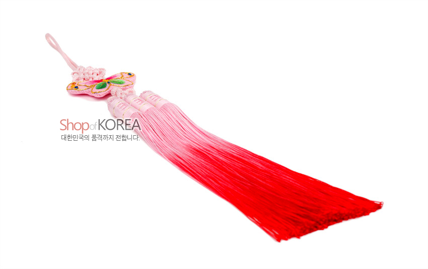 [텍스트: Shop of KOREA 대한민국의 품격까지 전합니다.] 분홍색 실 매듭과 화려한 자수 나비 장식, 연분홍에서 진홍으로 그라데이션된 삼가닥 술이 조화를 이룬 전통 노리개 이미지 설명