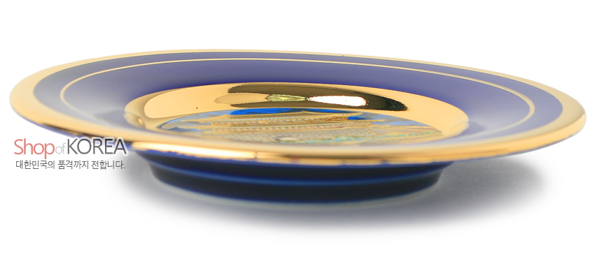 [텍스트: Shop of KOREA / 대한민국의 품격까지 전합니다.] 청색 바탕 위 금속 재질에 24K 금장 처리된 가장자리와 중앙 남대문 장식이 배치된 원형 접시 형태의 장식품