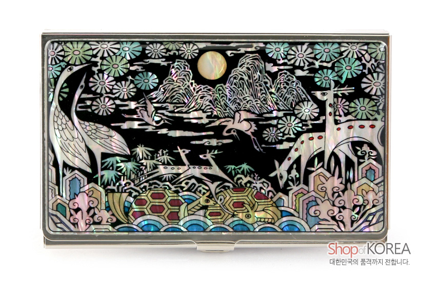 [텍스트: Shop of KOREA 대한민국의 품격까지 전합니다.] 흑색 바탕 금속 명함집 위 자개 상감 기법으로 십장생 산수와 학·사슴·거북, 연꽃과 구름 문양을 화려한 오색 광채로 표현한 디자인