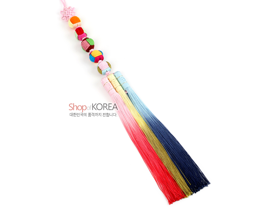 [텍스트: Shop of KOREA 대한민국의 품격까지 전합니다.] 색동 천 구슬 다섯 개를 전통 매듭으로 엮고 분홍·노랑·하늘·남색 실타래 술을 3단으로 늘어뜨린 노리개 장식