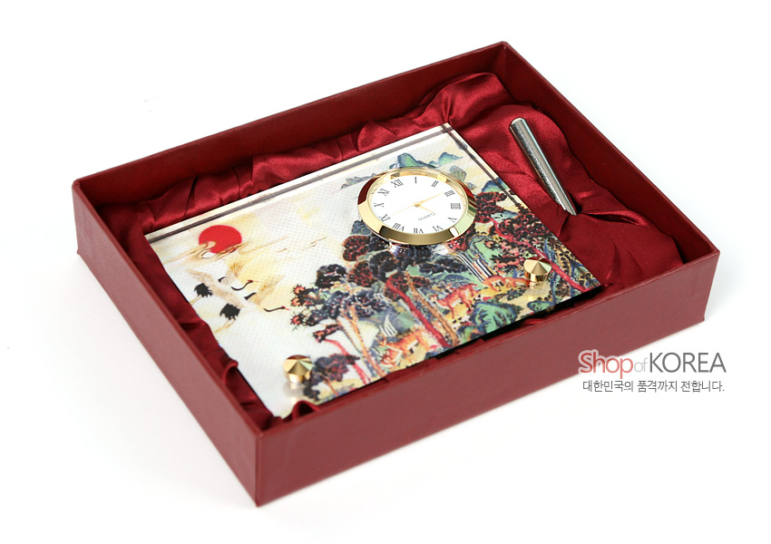 [텍스트: Shop of KOREA / 대한민국의 품격까지 전합니다.] 붉은 비단 안감 박스 속 금색 금속 테두리 원형 시계와 십장생 민화풍 산수·학 문양 탁상시계, 금속 볼펜 구성 이미지