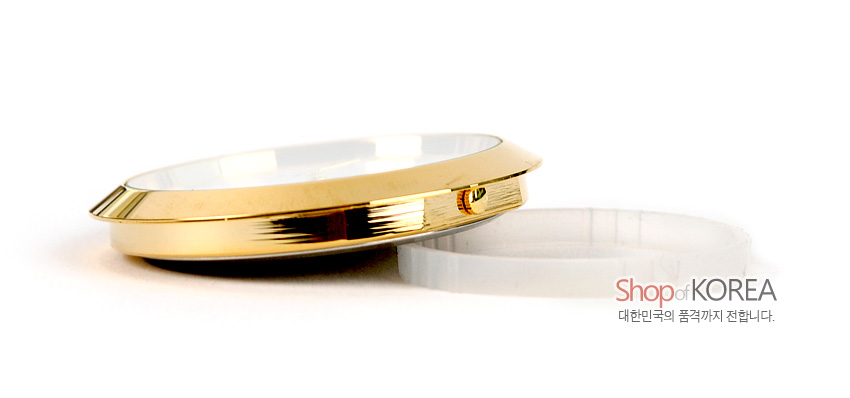 [텍스트: Shop of KOREA / 대한민국의 품격까지 전합니다.] 금색 금속 테두리와 투명 유리 표면, 흰색 원형 받침대로 구성된 시계 측면 클로즈업 이미지