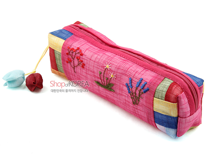 [텍스트: Shop of KOREA 대한민국의 품격까지 전달합니다.] 분홍 모시 천 위 꽃자수 장식과 오방색 조각천 배색, 버선코 모양 매듭 장식 지퍼 손잡이 필통 디자인