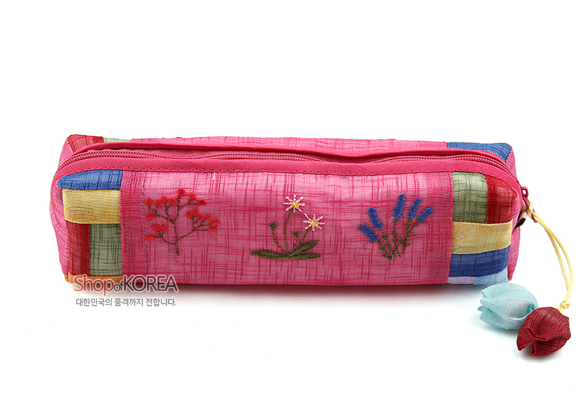 [텍스트: Shop of KOREA 대한민국의 품격까지 전합니다.] 분홍 모시 원단에 꽃자수 문양과 오방색 조각천 배색, 매듭 장식 지퍼 손잡이가 어우러진 필통 디자인