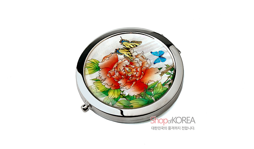 [텍스트: Shop of KOREA 대한민국의 품격까지 전합니다.] 자개 바탕 위에 붉은 목단꽃과 나비, 푸른 나뭇잎을 다채로운 채색으로 표현한 원형 금속 손거울 이미지 설명