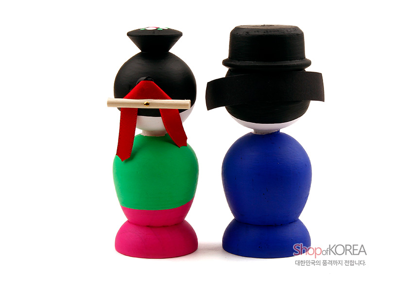 [텍스트: Shop of KOREA 대한민국의 품격까지 전합니다.] 목각으로 조형된 한복 혼례신랑신부 인형, 선명한 녹색·분홍·청색 채색과 검정 관모·머리장식이 대비되는 전통 의상 표현