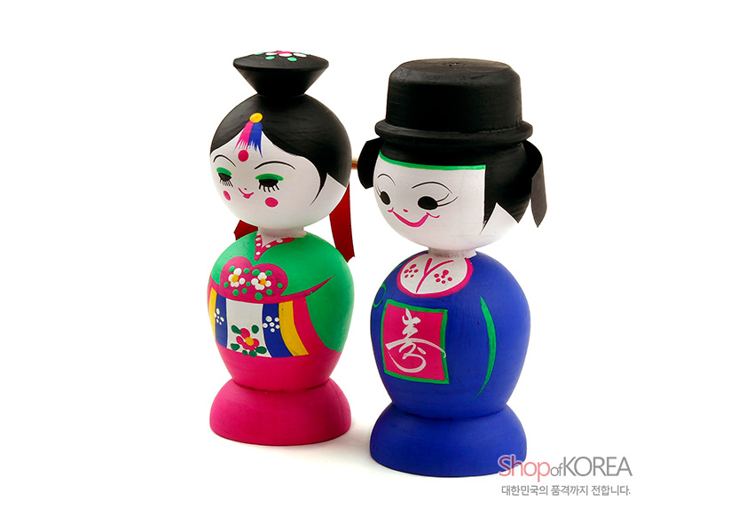 [텍스트: Shop of KOREA 대한민국의 품격까지 전합니다.] 원목 재질 위 아크릴 채색 기법, 한복 혼례복의 오방색 단청무늬와 수자 문양이 돋보이는 전통 목각신랑신부 인형 장식