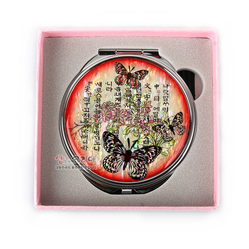 [텍스트: 나랏말싸미 듕귁에 달아 문자와로 서르 사맛디 아니할쎄...] 붉은 그러데이션 바탕 위 자개 상감 나비와 꽃, 훈민정음 서체 문양이 어우러진 금속 손거울 디자인