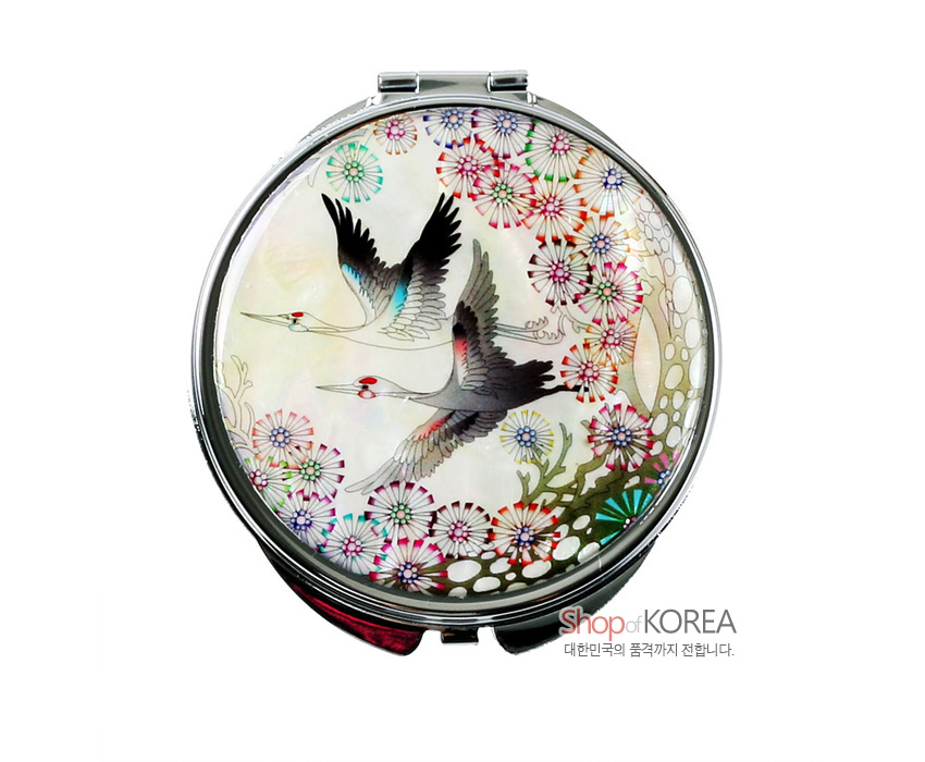 [텍스트: Shop of KOREA 대한민국의 품격까지 전합니다.] 자개 상감된 금속 손거울, 오팔빛 자개 바탕 위 쌍학과 다채로운 국화 문양을 섬세한 채색으로 표현한 디자인