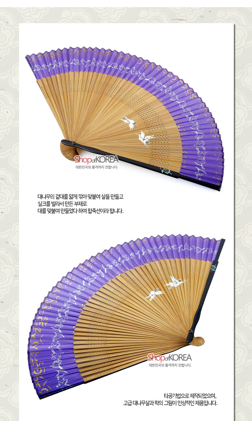 [텍스트: ShopofKOREA 대한민국의 품격까지 전합니다.] 자색 실크 면 위 은색·금색 학과 초화 문양 채색, 대나무살 타공 장식이 어우러진 합죽선 형식의 수공 부채