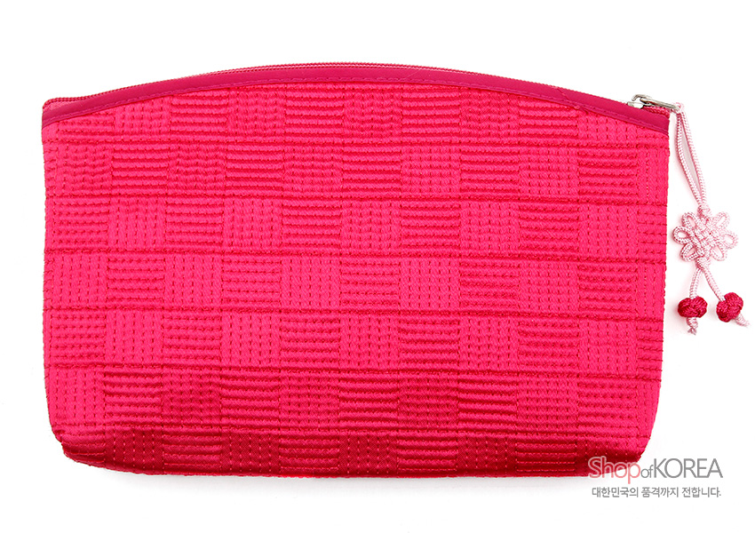 [텍스트: Shop of KOREA 대한민국의 품격까지 전합니다.] 분홍색 누비 비단 소재, 격자 무늬 질감과 지퍼 여밈, 배꽃 형태 매듭 장식이 돋보이는 파우치 이미지 설명