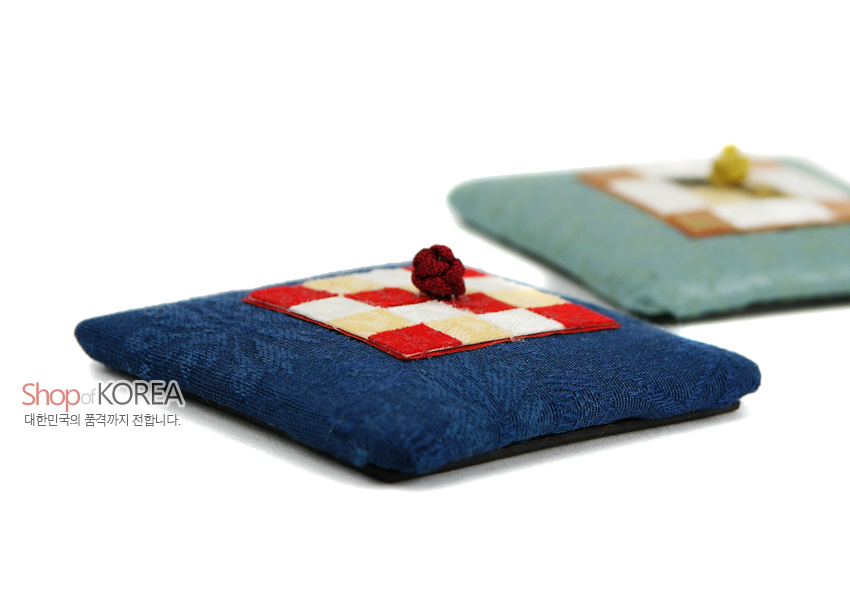 [텍스트: Shop of KOREA 대한민국의 품격까지 전합니다.] 짙은색 비단 바탕 위 전통 조각보 누비 사각 패치와 색실 연봉매듭이 어우러진 방석형 자석 장식