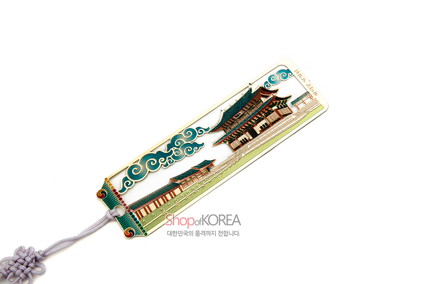 [텍스트: 창덕궁 인정전, Shop of KOREA 대한민국의 품격까지 전합니다.] 금속 재질 위에 녹청색 기와의 인정전과 구름무늬를 세밀 채색한 직사각 책갈피, 연보라 전통 매듭끈 장식 구성