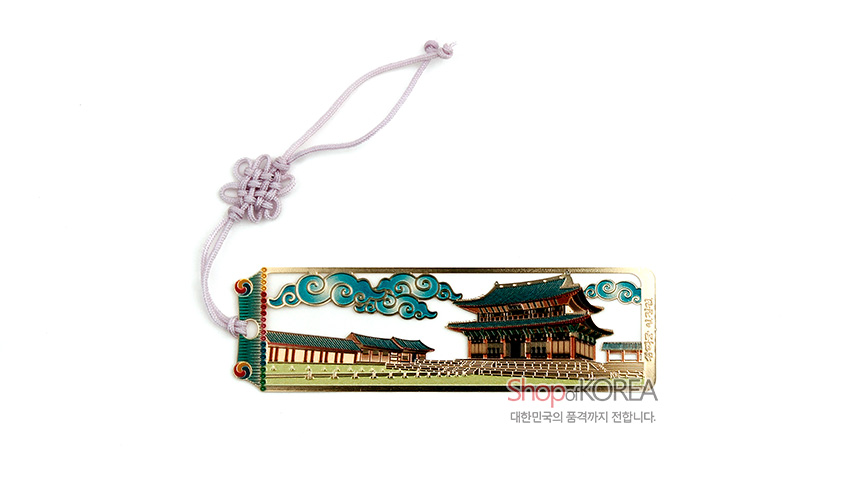 [텍스트: Shop of KOREA, 대한민국의 품격까지 전합니다.] 금색 금속 재질 위 창덕궁 인정전과 청록 운문을 섬세하게 채색한 직사각 책갈피, 연분홍 전통 매듭 끈 장식
