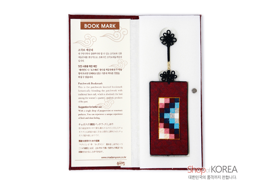 [텍스트: BOOK MARK / 조각보 책갈피 / www.mackmyoon.co.kr / Shop of KOREA 대한민국의 품격까지 전합니다.] 자주색 비단 직사각형 바탕에 분홍·남색·하늘색 등 다색 조각보 누비 장식이 중앙에 배치되고, 상단에 흑색 전통 매듭과 술이 이어진 책갈피 구성