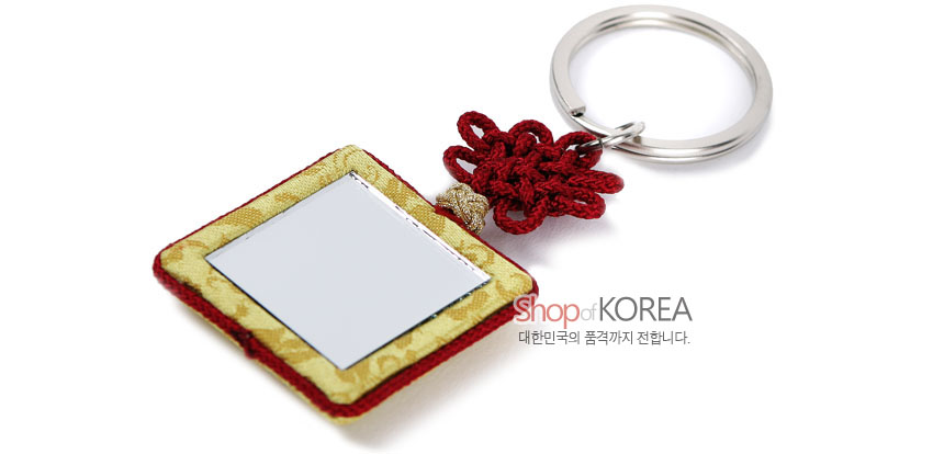 [텍스트: Shop of KOREA 대한민국의 품격까지 전합니다.] 황색 비단 바탕 사각 거울 장식과 붉은 전통 매듭, 은색 금속 링으로 구성된 조각보 열쇠고리 이미지 설명