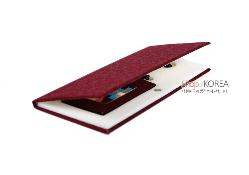 [텍스트: Shop of KOREA 대한민국의 품격까지 전합니다.] 자색 전통 문양 비단 케이스 속에 다색 조각보 장식 책갈피와 흑색 매듭 장식이 놓인 이미지